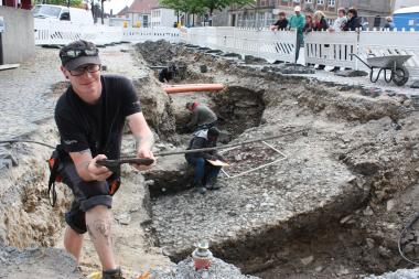 Etwa 700 Jahre wartete der hölzerne Unterschuh in den schlammigen Schichten über dem Platzpflaster (im Hintergrund) auf seine Entdeckung durch Grabungsmitarbeiter Mirko Bahr (vorne links). <br>Foto: LWL/Spiong