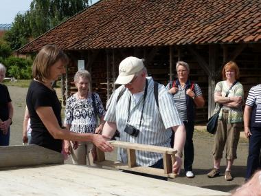 Museumspädagogin Astrid Weise erklärt den Besuchern, wie die Ziegel mit einem Streichrahmen hergestellt werden.<br>Foto: LWL
