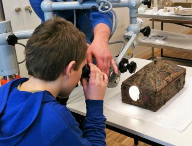 Schüler schaut durch ein Mikroskop beim Besuch der Restaurierungs-Werkstatt im LWL-Museum für Kunst und Kultur. <br>Foto: LWL/Schmidt