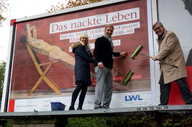 Martina Brandherm, Münster Marketing, Hermann Meyersick, Firma Ströer, und Dr. Hermann Arnhold, LWL-Museum für Kunst und Kultur, (v. l.) klebten das Plakat der Kampagne auf eine Werbefläche am Hauptbahnhof Münster.<br>Foto: LWL