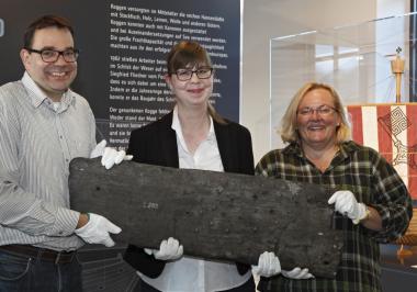 LWL-Museumsleiter Dr. Arnulf Siebeneicker (v.l.), Kuratorin Linda Wilken und Restauratorin Renate Uphoff mit einer originalen Planke der "Bremer Kogge" aus dem 14. Jahrhundert. <br>Foto: LWL/Holtappels 