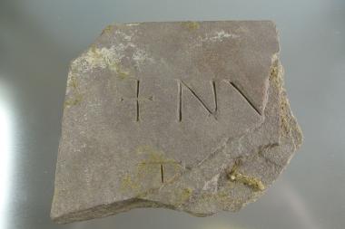 Ein Bruchstück von einem Sandstein mit Inschrift. Es lag zwar in einer Erdschicht des 11. Jahrhunderts. <br>Foto: LWL/Spiong