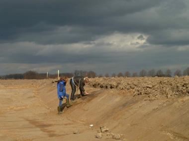 Dr. Eva Cichy und Norbert Reuther M.A. von der Außenstelle Olpe der LWL-Archäologie für Westfalen bei Entdeckung der erster Gruben (schwarze Flecken) der neuen Fundstelle in der Wand eines Regenrückhaltebeckens. <br>Foto: LW/Baales
