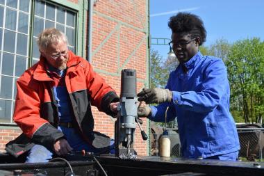 Schlosser Werner Lammers erklärt Koli Kanté die Bedienung des Bohrers. <br>Foto: LWL