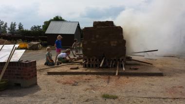 Die Kinder befeuern den Feldbrandofen.<br>Foto: LWL