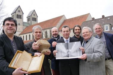 (v.l) Michael Pavilic, Dr. Martin Kroker, Michael Hoffmann, Dr. Eckhard Düker, Dr. Andreas Neuwöhner, Prof. Hermann-Josef Schmalor, Dr. Roland Linde präsentieren im Schatten der Abdinghofkirche Exponate für die bevorstehende Ausstellung und das Programm für die Veranstaltungen und die Tagung zum 1000-jährigen des Klosters.<br> Foto: LWL/Burgemeister<br><b><i>Ausführlichere Bildunterzeile am Ende des Pressetextes.</b></i>