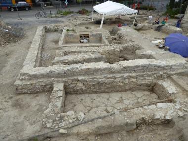 Überblick über die Grabungsfläche: Im Vordergrund ist der Keller eines Hauses aus dem 15. Jahrhundert zu sehen, darüber liegt die ehemalige Klostermauer aus dem 17. Jahrhundert. In der Mitte der Betonbau eines Bier- bzw. Eiskellers einer Gastwirtschaft, die bis zur unmittelbaren Zeit nach dem Zweiten Weltkrieg hier gestanden hat.<br>Foto: LWL/Manz
