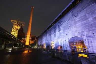 Im Schatten des beleuchteten Hochofens erkunden die Teilnehmer die Industriebrache. Foto: LWL/Hudemann