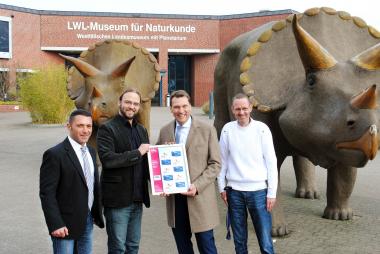 Die Übergabe der Marken zur Ausstellung "Wasser bewegt" erfolgte unter den Augen der Dinosaurier des LWL-Museums durch (v.li.n.re.) Projektleiter Ciro Lenti (Brief und mehr), Museumsdirektor Dr. Jan Ole Kriegs, Geschäftsführer Marco Morocutti von Brief und mehr sowie dem Leiter des Bereiches Besucherservice, Rolf Bergmeier (LWL-Museum).<br>Foto: LWL/Heimann