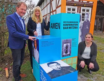 Auf großen Würfeln im Museumsgelände werden verschiedene Themen rund um die Kindheit präsentiert. An der Geländestation am Pastorat geht es um Erstkommunion, Konfirmation und Bar Mitzwa, wie LWL-Museumsdirektor Prof. Dr. Jan Carstensen, LWL-Kulturdezernentin Dr. Barbara Rüschoff-Thale und Ausstellungskuratorin Corinna Keunecke (v. l.) erläuterten.<br>Foto: LWL/Jähne