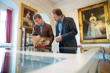 Stephan Prinz zur Lippe zeigt LWL-Museumsdirektor Prof. Dr. Jan Carstensen die Kindheitsobjekte, die es im Rahmen der neuen Führungsreihe "Kindheit im Schloss" zu sehen gibt.<br>Foto: LWL/Hesterbrink/Pölert