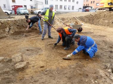 Nach dem Bagger kommt die Handarbeit: Das Grabungsteam säubert mit Kelle und Kratzer eine der aufgedeckten Flächen. Links im Bild zeichnet sich als dunkle Verfärbung eine rundliche Grube ab.<br>Foto: LWL-Archäologie für Westfalen/J. Hallenkamp-Lumpe