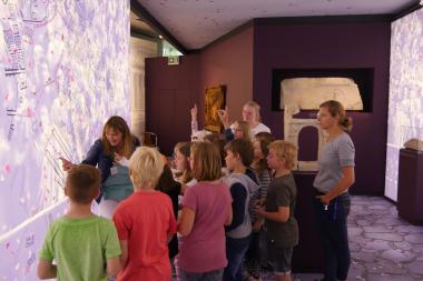 Spielerisch führt die Museumspädagogin Sabine Holländer sowohl Erwachsene als auch Kinder durch die Sonderausstellung "Triumph ohne Sieg" im LWL-Römermuseum.<br>Foto: LWL/Steimer