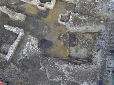 Das Luftbild eines Teils der Grabungsfläche zeigt neben den Mauern von Kellern und Parzellengrenzen auch die dunklen Verfärbungen der hochmittelalterlichen Gruben und Pfostenlöcher.<br>Foto: EggensteinExca, R. Gündchen