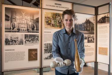 Phillip Berg vom Ausstellungsteam mit Hantel und Gymnastikkeule, die im 19. Jahrhundert beim Turnen im "Deutschen Haus" in Indianapolis zum Einsatz kamen.<br>Foto: LWL/Hudemann