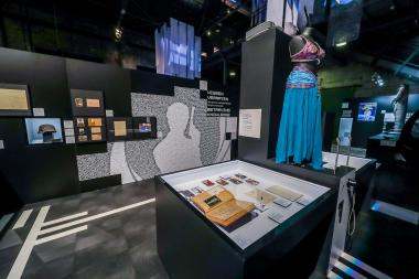 Inszenierung zu Mata Hari in der Ausstellung "Alles nur geklaut?". Im Vordergrund die Vitrine mit Dokumenten und einem persönlichen Album der Tänzerin, in dem sie Presseartikel und Plakate zu ihren Auftritten sammelte. Im Hintergrund das Kostüm, das die Schauspielerin Natalia Wörner im Spielfilm "Mata Hari - Tanz mit dem Tod" (2017) trug.<br>Foto: LWL/Schütze