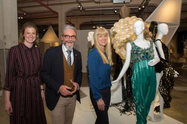 Christa Frins, Martin Schmidt und LWL-Kulturdezernentin Dr. Barbara Rüschoff-Parzinger (v.l.) stellten die Ausstellung "Fashion Material. Modewelten von Stephan Hann" in Bocholt vor. Im Foto die Kreation "Peacock" - ein Kleid aus Pfauenfedern aus Papier und CDs.<br>Foto: LWL/Hudemann