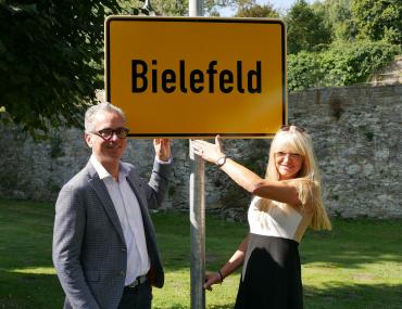 Bielefeld-Verschwörung: Museumsdirektor Dr. Ingo Grabowsky und Kulturdezernentin Dr. Barbara Rüschoff-Parzinger schüren die Gerüchte um die Nichtexistenz der Stadt. Ein Ortsschild beweist: Bielefeld gibt es nicht in Bielefeld, aber im Kloster Dalheim.<br>Foto: LWL/Kristina Schellenberg