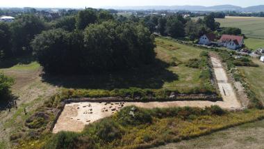 Drohenfoto vom Nordwesten: Vorne links im Grabungsschnitt sind die untersuchten Pfostenlochreihen zu sehen. Dahinter liegt leicht erhöht hinter den Bäumen der "von Oeynhausen'schen Hof". Im Grabungsschnitt rechts deutet sich der südliche Hofgraben als dunkle Verfärbung an.<br>Foto: LWL-Archäologie für Westfalen/Andreas Wibbe