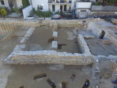 Blick von Osten auf die Punktfundamente und Grundmauer des Gebäudekomplexes, das an dem Keller südlich anschließt. Rechts ist der südliche spätere Zugang in den Keller.<br>Foto: EggensteinExca / Süße