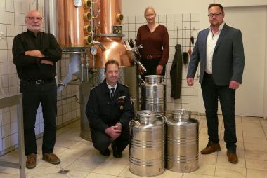 In der Dalheimer Brennerei übergeben Brenner Hermann Zinser (l.) und Volontärin Katharina Kruck das Destillat an Marcus Siekaup, stellv. Leiter der Feuerwehr Bad Wünnenberg (u. l.) und Julian Clausmeyer vom Ordnungsamt Bad Wünnenberg (r.).<br>Foto: LWL/Kristina Schellenberg