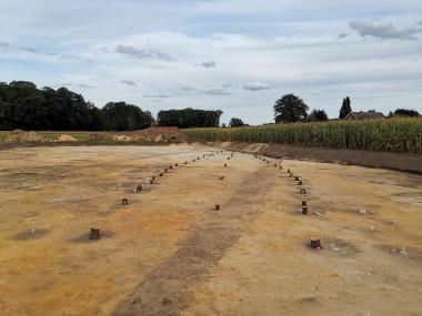 Die mit Holzklötzen markierten Standorte der Pfosten verdeutlichen den schiffsförmigen Hausgrundriss des 9./10. Jahrhundert.<br>Foto: Sebastian Luke/Archäologie am Hellweg e.G.