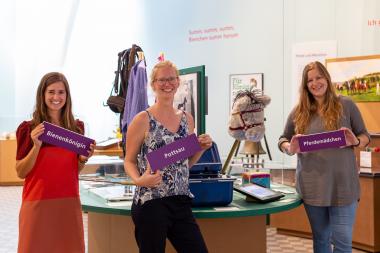 Die Ausstellungskuratorinnen Lisa Egeri, Julia Bursa und Jana Golombek (v.l.) stehen am Eröffnungstag (17.3.) in der Ausstellung für Fragen bereit. Besucher:innen können sich mit Namensschildern in einer Fotobox ablichten.<br>Foto: LWL/Gehrmann.