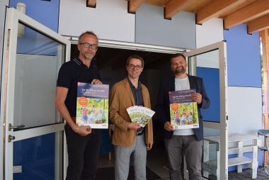 Pflegedirektor Thomas Linnemann, der Ärztliche Direktor Prof. Dr. Dr. Martin Holtmann und der Kaufmännische Direktor Dr. Daniel Napieralski-Rahn (v. li.) freuen sich, endlich wieder zum "Tag der offenen Tür" auf das Gelände der LWL-Universitätsklinik für Kinder- und Jugendpsy-chiatrie einladen zu dürfen. Vor der "Arche", dem Neubau für die begleitende tiergestützte Therapie, präsentieren sie Plakate und Flyer.<br>Foto: LWL
