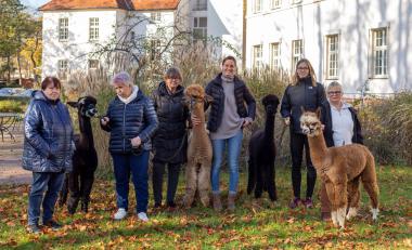 Gruppe mit Alpakas.jpg: Heike Wilms (ganz r.) und Eva Meintrup (3.v.r.) freuten sich, dass der Spaziergang mit den Alpakas auf dem Gelände des LWL-Klinikums Gütersloh so großen Anklang bei den Patientinnen und Patienten gefunden hat.<br>Foto: LWL