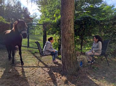 &quot;Es war ein spannender Tag, viele Patienten haben ihn besucht und er fand die Aufmerksamkeit sehr gut&quot;, erzählt Dr. Mara Herda. Beim Dienstgespräch im schattigen Garten hat das Pferd nicht gestört.&lt;br&gt;Foto: LWL 
