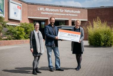 Dr. Annegret Saxe (v.re.n.li.) vom Stiftungsvorstand übergab im Namen der Stiftung der Sparkasse Münsterland Ost einen Scheck an LWL-Museumsdirektor Dr. Jan Ole Kriegs und Ausstellungskuratorin Lisa Wong.&lt;br&gt;Foto. LWL/Steinweg 