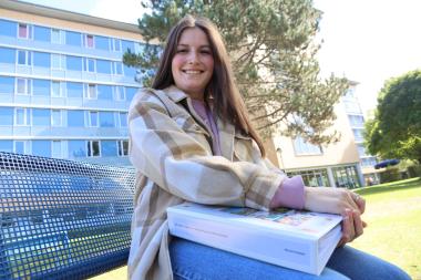 Sarah Rath ist eine der pflegerischen Mitarbeiterinnen, die das Onboarding-Konzept durchlaufen haben. Unser Foto zeigt sie mit der persönlichen Mappe in der Hand auf dem Gelände der LWL-Klinik an der Agathastraße.<br>Foto: LWL/Dresmann