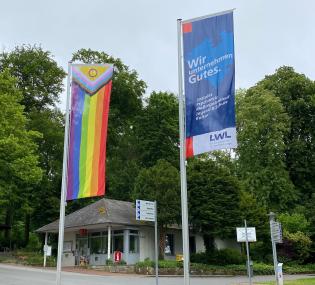 Die LWL-Klinik Lengerich setzt mit dem Hissen der "Progress Pride-Flagge" neben der LWL-Flagge am Parkeingang ein deutliches Zeichen auch nach außen hin.<br>Foto: LWL/Sandra Kätker