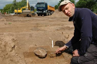 Beschädigt, aber dennoch ein wichtiger Fund: Die Reste dieses Urnengrabs werden von Christoph Storz von der Fachfirma Archäologie am Hellweg eG freigelegt.<br>Foto: LWL/ Düvel