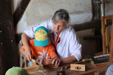 Die Mitarbeiter:innen des Freilichtmuseums zeigen auch den kleinen Museumsgästen, wie sie bei verschiedenen Gewerken mit anpacken können.<br>Foto: LWL/Gerstendorf-Welle
