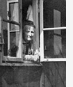 Frau am Fenster einer Nissenhütte im Altenheim des Sozialwerks Stukenbrock / Fotoarchiv: Gerd Plückelmann, Witten