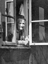 Frau am Fenster einer Nissenhütte im Altenheim des Sozialwerks Stukenbrock / Fotoarchiv: Gerd Plückelmann, Witten