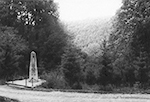 Obelisk für die ermordeten Zwangsarbeiter mit der aufgeforsteten Grabanlage in Suttrop. Aufnahme des Landeskriminalamts NRW aus der "Bildmappe zur Erschießung von Fremdarbeitern im Raum Warstein, Suttrop u. Eversberg, Bz. Arnsberg im März 1945" / Landesarchiv NRW Abteilung Westfalen