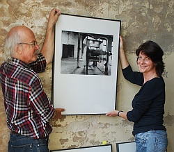 Die Fotografen Berthold Socha und Anke Hochgartz hängen ein Foto an die Wand.