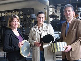 Christine Krogull (mitte) übergibt den Samt-Hut von Marilyn Monroe samt Originalhutschachtel, den sie in den USA ersteigert hat, an LWL-Museumsleiter Hermann-Josef Stenkamp (rechts) und Claudia Gottfried (links) vom Rheinischen Industriemuseum Ratingen. Foto: LWL