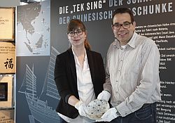Linda Wilken und Dr. Arnulf Siebeneicker mit einem Teller aus dem Wrack der 1822 gesunkenen chinesischen Dschunke Tek Sing.