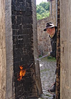 Karl Manfred Rennertz beim Schwärzen einer Holzskulptur auf der Zeche Nachtigall. Foto: LWL